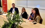 Uczestnicy panelu dyskusyjnego siedzący za stołem prezydialnym.