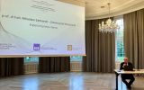 Prelegent wygłasza referat „Imperium prawa islamu” przy wyświetlonym slajdzie tytułowym.