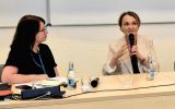 Uczestniczka panelu wypowiada się do mikrofonu podczas dyskusji na II Forum Cooperante. Obok niej siedzi druga uczestniczka.