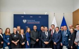Uczestnicy spotkania pozują w sali Ministerstwa Nauki i Szkolnictwa Wyższego na tle baneru z oznaczeniem MNiSW oraz flag Polski i Unii Europejskiej.