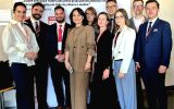 Uczestnicy II Forum Cooperante pozują do wspólnego zdjęcia przy ściance z logo wydarzenia.