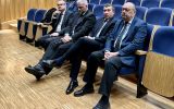 Czterech mężczyzn w garniturach siedzi w pierwszym rzędzie auli podczas uroczystości immatrykulacji.