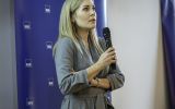 Prelegentka przemawia na tle ścianki Wydziału Prawa i Administracji UR.