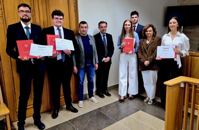 Laureaci i organizatorzy pozują w sali rozpraw z dyplomami oraz egzemplarzami Konstytucji Rzeczypospolitej Polskiej.
