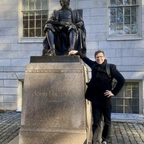 Zdjęcie przedstawiające doktora Joachima Popka przy pomniku Johna Harvarda