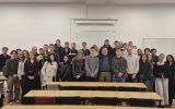 Zdjęcie grupowe studentów pozujących w sali wykładowej.