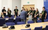 Grupa studentów w czarnych koszulkach z napisem „POWER”. Przed nimi stoi rektor UR.