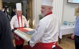 Kucharze wnoszą tort udekorowany motywami Polski i Unii Europejskiej podczas wydarzenia w Podkarpackim Urzędzie Wojewódzkim.