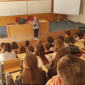 Widok ogólny. mgr Magdalena Suraj przemawia do słuchaczy. W tle slajd prezentujący tytuł warsztatu: „Oszczędzanie - to brzmi dumnie!”