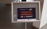 Tablica informacyjna w budynku z napisem „Witamy na konferencji UR AI Summit” oraz logotypami organizatorów i partnerów wydarzenia.