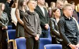 Grupa studentów i innych uczestników uroczystości stoi w auli podczas immatrykulacji.