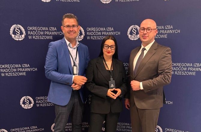 Uczestniczka konferencji pozuje z dwoma uczestnikami wydarzenia na tle ścianki Okręgowej Izby Radców Prawnych w Rzeszowie.