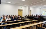 Studenci siedzący w ławkach w sali wykładowej.