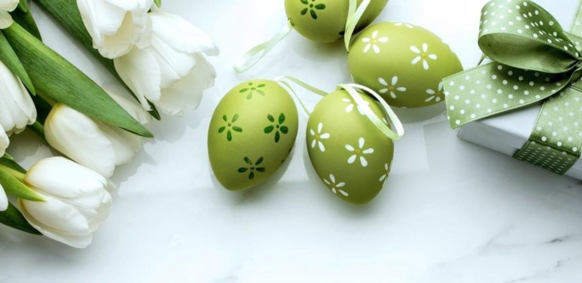 jajka wielkanocne, kwiaty i prezent leżą na stole