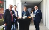 Uczestnicy konferencji rozmawiają podczas przerwy przy stoliku koktajlowym.
