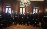 Grupa uczestników międzynarodowego spotkania prawniczego pozuje w reprezentacyjnej sali z drewnianym wystrojem i kryształowym żyrandolem.