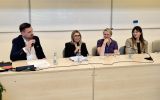 Prelegenci panelu dyskusyjnego rozmawiają przy stole konferencyjnym.