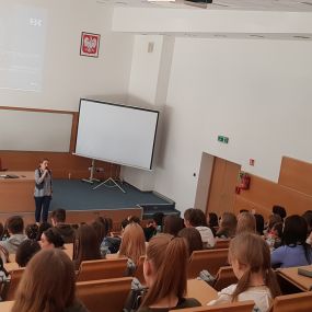 Widok ogólny. mgr Magdalena Suraj przemawia do słuchaczy. W tle slajd prezentujący tytuł warsztatu: „Oszczędzanie - to brzmi dumnie!”