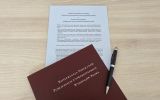 Dokument zatytułowany „Deklaracja Współpracy” leży na stole częściowo przykryty bordową teczką z napisem „Konferencja Dziekanów Publicznych Uniwersyteckich Wydziałów Prawa”. Obok znajduje się długopis.