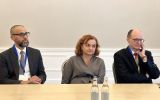 Trzy osoby siedzą przy stole podczas obrad konferencyjnych.