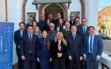 Grupa uczestników międzynarodowego spotkania prawniczego pozuje przed budynkiem instytucji sądowniczej w Buenos Aires; obok widoczny jest baner organizatora.