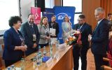 Uczestnicy konferencji wręczają bukiet kwiatów jednej z osób podczas części uroczystej wydarzenia.