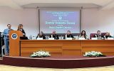 Sala uroczystości akademickiej z prezydium i ekranem informującym o nadaniu tytułu Doctor Honoris Causa.