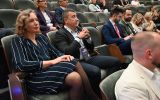 Uczestnicy konferencji siedzący w rzędach w audytorium. Na pierwszym planie widoczne są osoby słuchające wystąpienia.