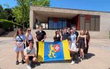 Studenci ELSA Rzeszów trzymają flagę z herbem Rzeszowa przed budynkiem w Schengen.