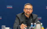 Przedstawiciel Ministerstwa Nauki i Szkolnictwa Wyższego siedzi przy stole podczas spotkania z dziekanami publicznych uniwersyteckich wydziałów prawa.