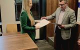 Uczestniczka wydarzenia odbiera dyplom od przedstawiciela organizatorów.