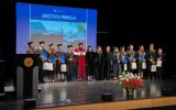 Grupowe ujęcie absolwentek i absolwentów w togach wraz z władzami Wydziału Prawa i Administracji na scenie.