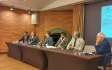 Sześcioro uczestników debaty siedzi za stołem konferencyjnym podczas XX Krakowskiego Seminarium Samorządu Terytorialnego w Wieliczce. W tle widoczny jest ekran z informacją o wydarzeniu.