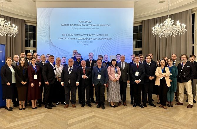Grupowe zdjęcie uczestników XXIII Zjazdu Katedr Doktryn Polityczno-Prawnych na tle ekranu konferencji.
