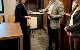 Uczestniczka wydarzenia odbiera dyplom od przedstawiciela organizatorów.