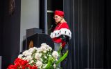 Prorektor przemawia z mównicy podczas uroczystej promocji absolwentów.