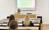 Prowadząca omawiająca prezentację o pełnej zdolności do czynności prawnych w sali wykładowej.