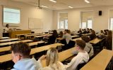 Uczestnicy siedzący w dużej sali wykładowej i słuchający prezentacji o mediacji sądowej.