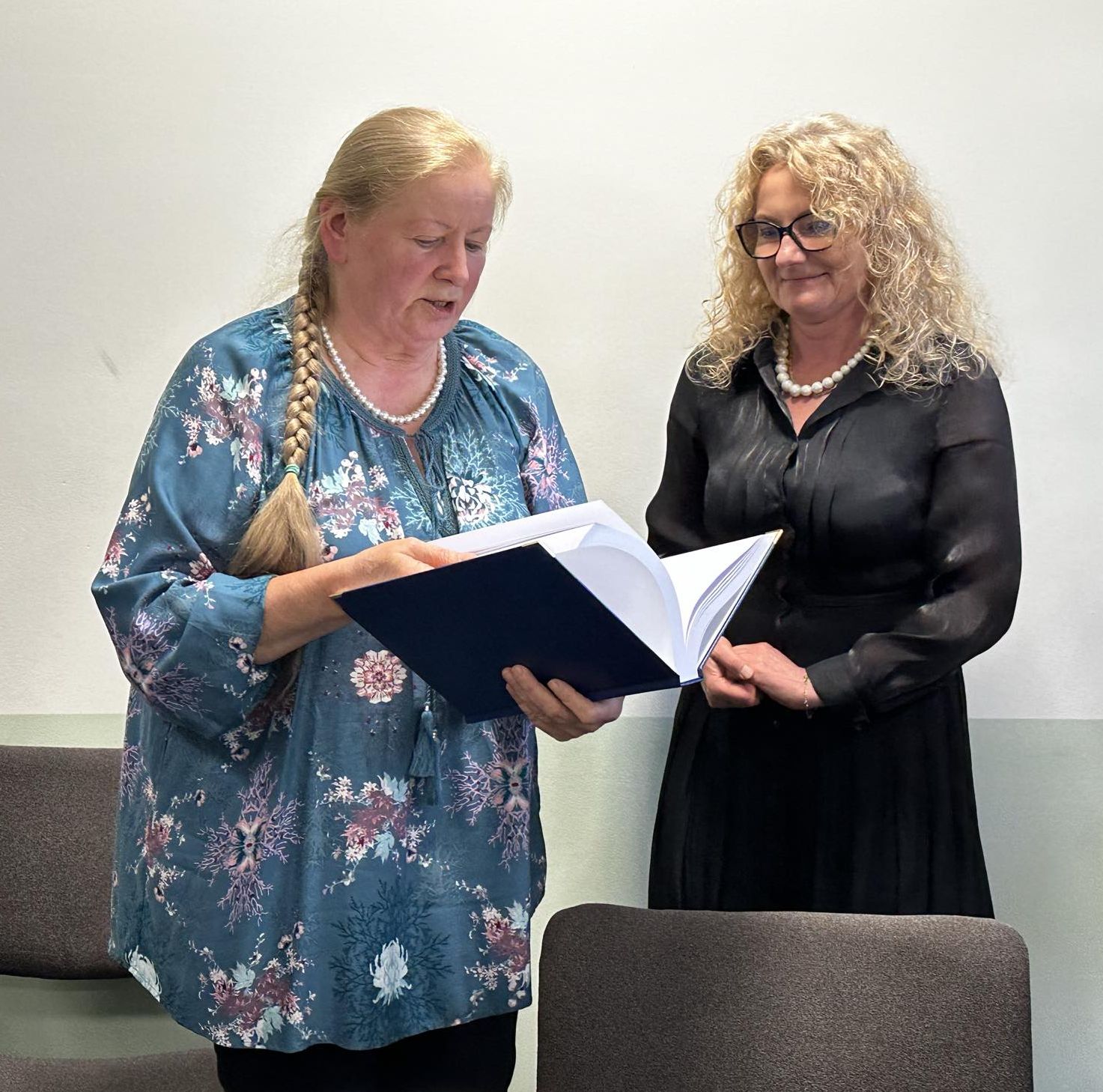 Prof Czyż i porf Stanek-Tarkowska stoją w sali, prof Czyz przegląda książkę