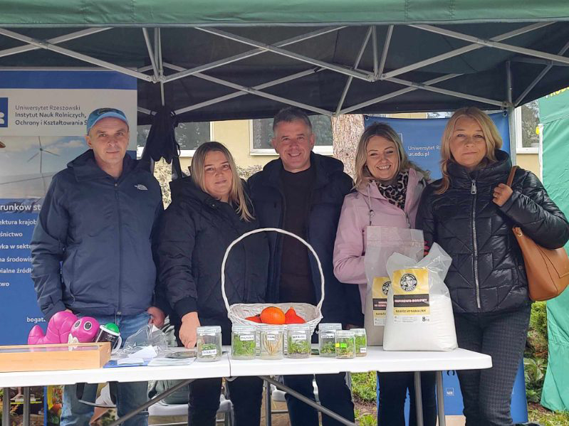 pracownicy instytutu pozują do zdjęcia pod namiotem, w tle baner UR