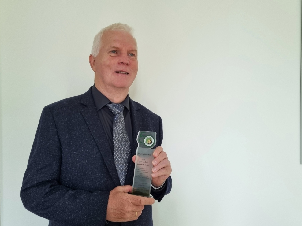 Prof Kukuła trzyma w ręku statuetkę z podziękowaniami