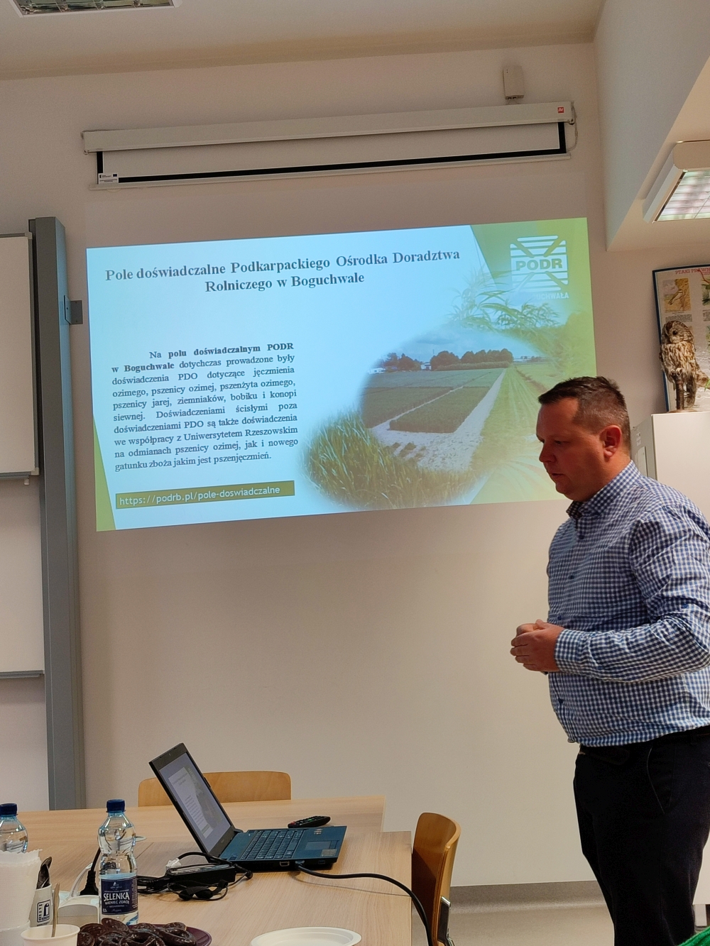 Prelegent przy prezentacji, na slajdzie pole uprawne