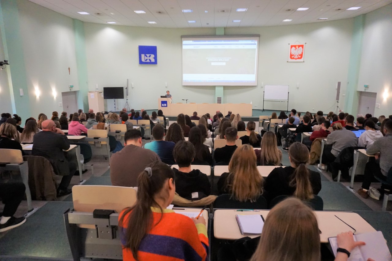 Uczestnicy spotkania w auli wykładowej, w tle prezentacja