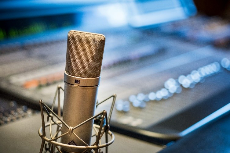Zbliżenie na srebrny mikrofon położony obok miksera audio, gotowy do nagrań studyjnych lub transmisji dźwiękowej.